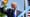 Donald Trump en costume sombre et cravate bleue lève le poing devant un microphone, en extérieur. Un bandeau bleu porte la mention « Partie 2 ».